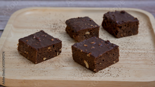 Chocolate brownies nuts squares on wooden plate.