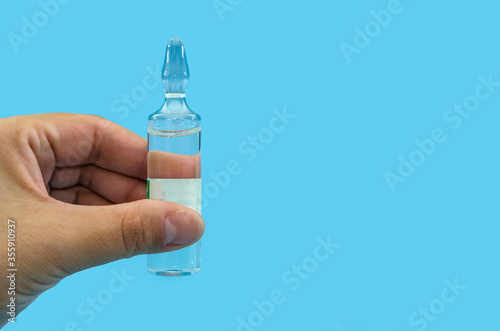 Ampule in hand isolated on a blue background. The concept of vaccination, health. Close-up. Copy of space. place for illustrations.
