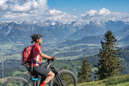pretty senior woman riding her electric mountain bike on the mountains above the Iller valley between Sonthofen and Oberstdorf, Allgau Alps, Bavaria Germany  © Uwe