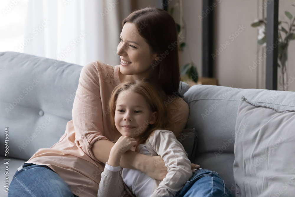 Loving young Caucasian mother and small preschooler daughter sit relax on couch in living room enjoy family leisure weekend together, happy mom and little girl child hug cuddle rest on sofa at home Loving young Caucasian mother and small preschooler daughter sit relax on couch in living room enjoy family leisure weekend together, happy mom and little girl child hug cuddle rest on sofa at home