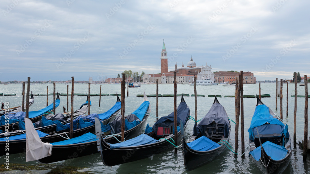 A row of gondolas and Church of San Giorgio Maggiore on the Island of Saint Giorgio Maggiore in the background, Venice, Italy
