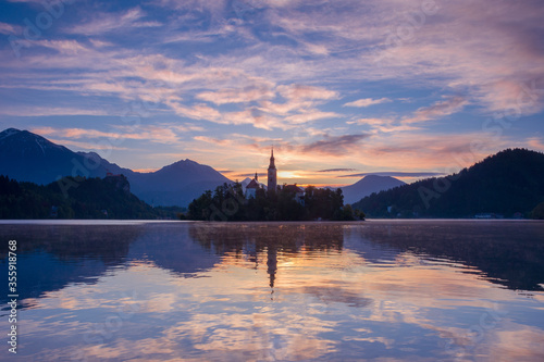 Beautiful sunrise and reflection at Lake Bled with the lake island and charming little church dedicated to the Assumption of Mary, famous tourist attraction in Slovenia
