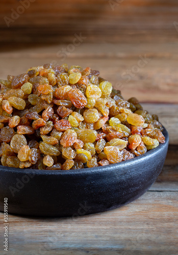 Golden Raisins in the bowl on wooden rustic background 