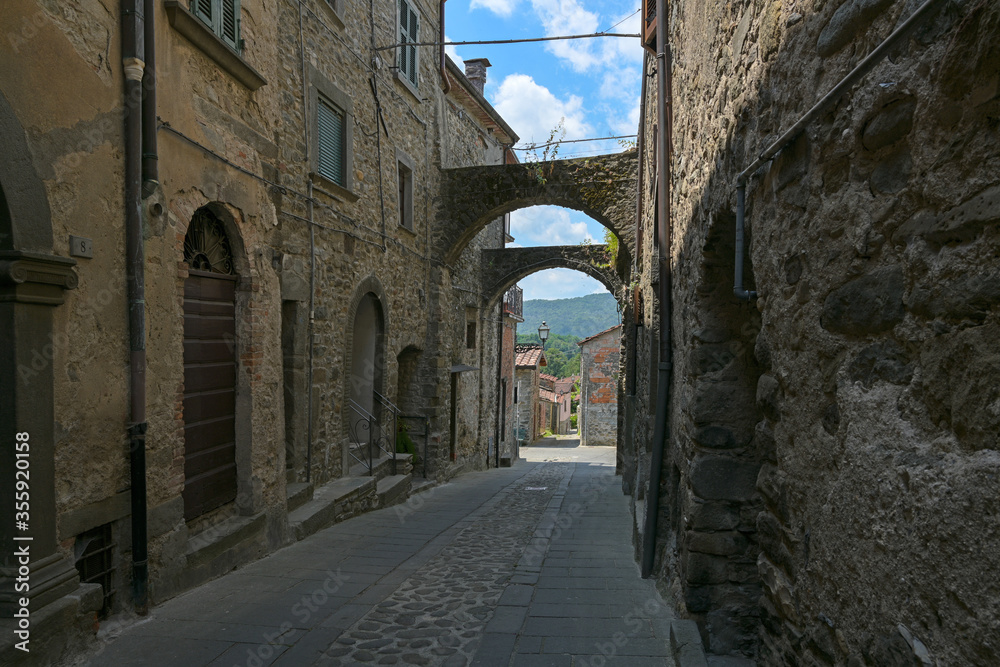 Narrow alley in Virgoletta, a beautiful ancient mountain village, empty during coronavirus pandemic, district of Villafranca in Lunigiana, Tuscany, Italy, blue sky