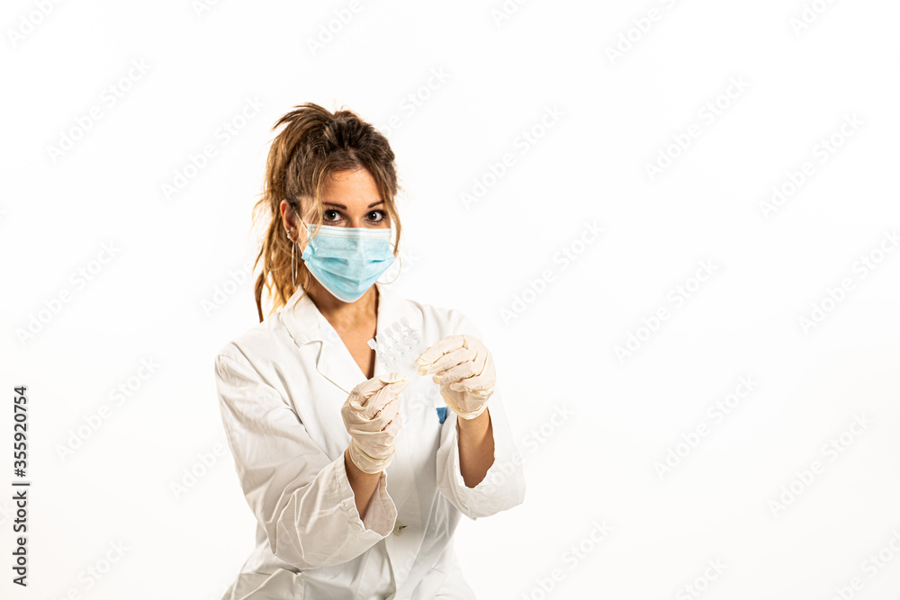 Woman wearing medical uniform showing phials on a white background. Woman wearing medical uniform showing phials on a white background.