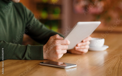 Man holding digital tablet, having coffee break at cafe