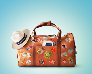 Vacation concept, large classic brown leather travel bag with hat