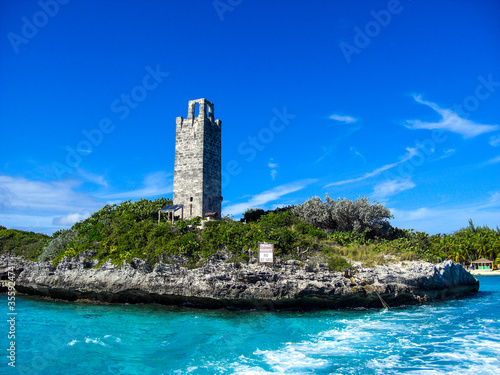 Blue Lagoon Island (Salt Cay), The Bahamas - December 22, 2014: Ancient stone tower at the gate to Blue Lagoon Island on The Bahamas surrounded by crystal  clear blue water.