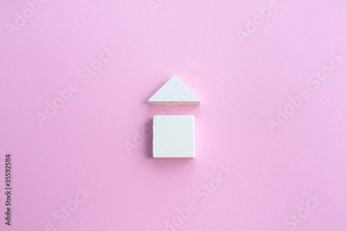 wooden house made of wooden geometric details on a pink background. Family home concept