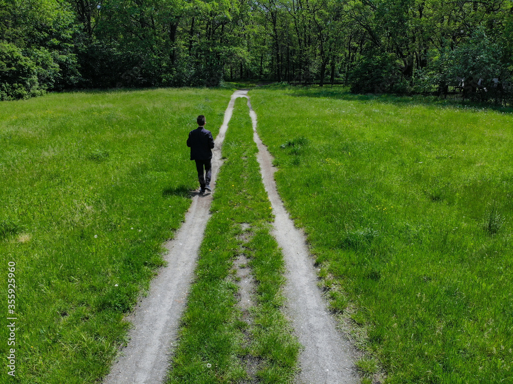 Man on double path at green clearing with trees around Man on double path at green clearing with trees around