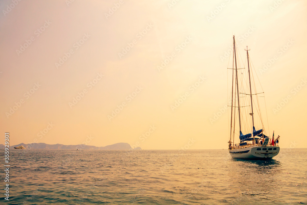 Sailboat at sea near the coast of Sicily at sunrise. Sailing yacht.