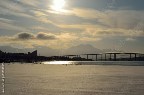 warming sunrise over snowy field and mountain with cathedral and tromsoe city island and mainland in the background
