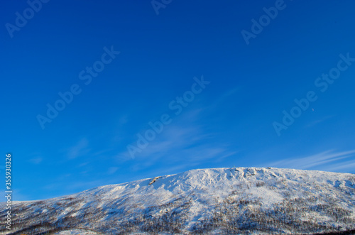 vibrant snowy mountain peak at sunrise on blue sky