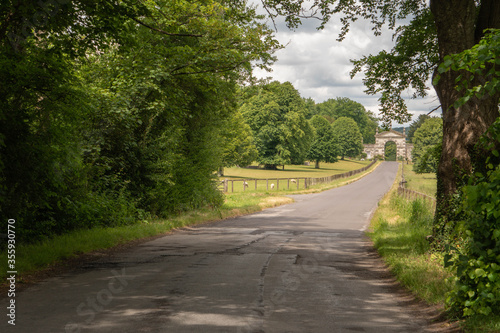 Long road leading down to the impressive gates of the Fonthill estate in the English countryside situated in Wiltshire, South West England photo