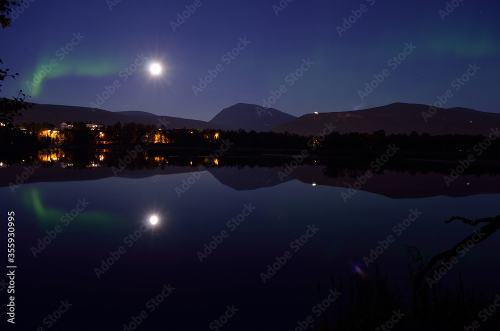 majestic aurora borealis, northern light over calm mirror lake at night with buildings in the background majestic aurora borealis, northern light over calm mirror lake at night with buildings in the background