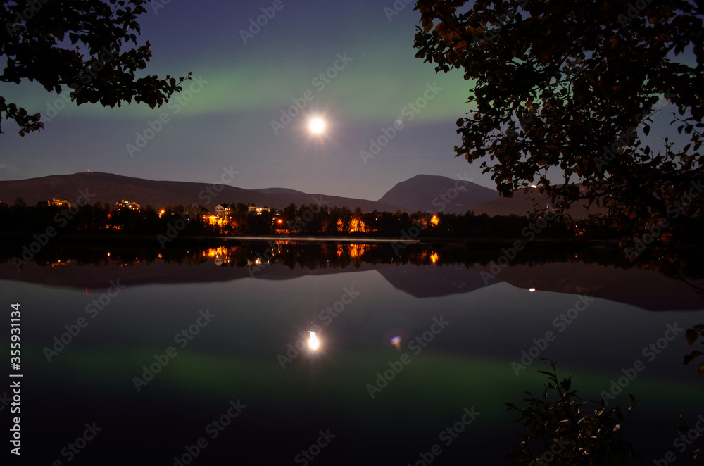 majestic aurora borealis, northern light over calm mirror lake at night with buildings in the background majestic aurora borealis, northern light over calm mirror lake at night with buildings in the background