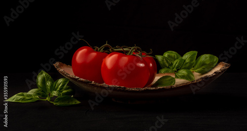 Frische Tomaten und Basilikum in Holzschale