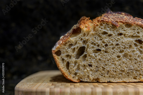 Sliced loaf of artisanal whole wheat and dark rye rustic sourdough bread on a cutting board, baked at home, photo series