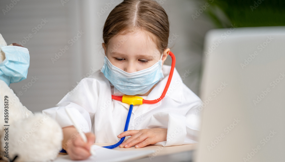 charming little girl in a white coat and mask, treats a Teddy bear charming little girl in a white coat and mask, treats a Teddy bear