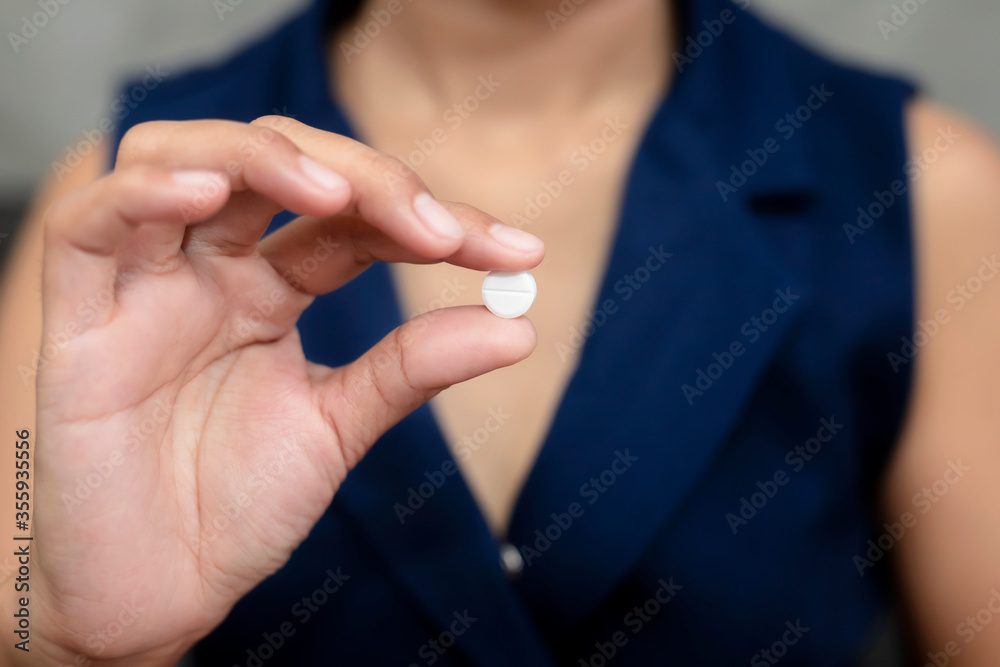 Close up of working woman taking in pill she is pours the pills out of the bottle,taking painkiller to reduce sharp ache concept,health care and medicine concept.