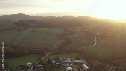 Cinematic drone / Aerial fly over shot of a sunset of a little village at a beautiful, vibrant color sunset, Oelberg, Siebengebirge, Bonn, Königswinter 25p photo