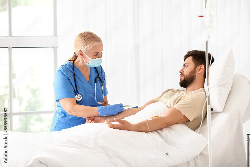 Fototapeta premium Mature female doctor working with patient in hospital room