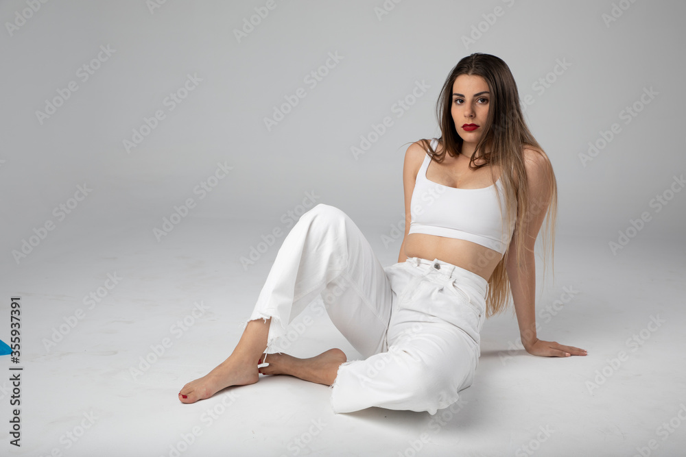 Modelo joven sentada sobre fondo blanco y ropa blanca con pelo largo Modelo joven sentada sobre fondo blanco y ropa blanca con pelo largo
