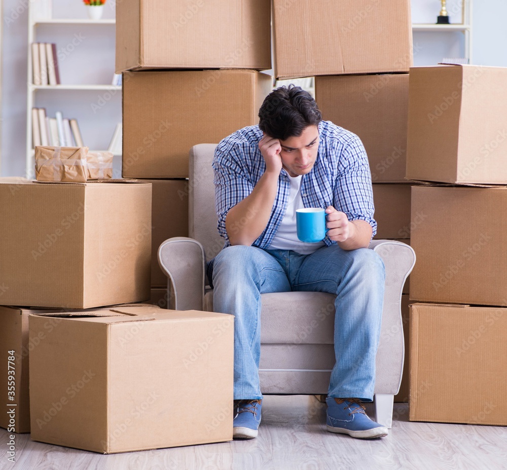 Young man moving in to new house with boxes Young man moving in to new house with boxes
