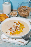 healthy smoothie bowl with mango, coconut and nuts for breakfast, vertical closeup