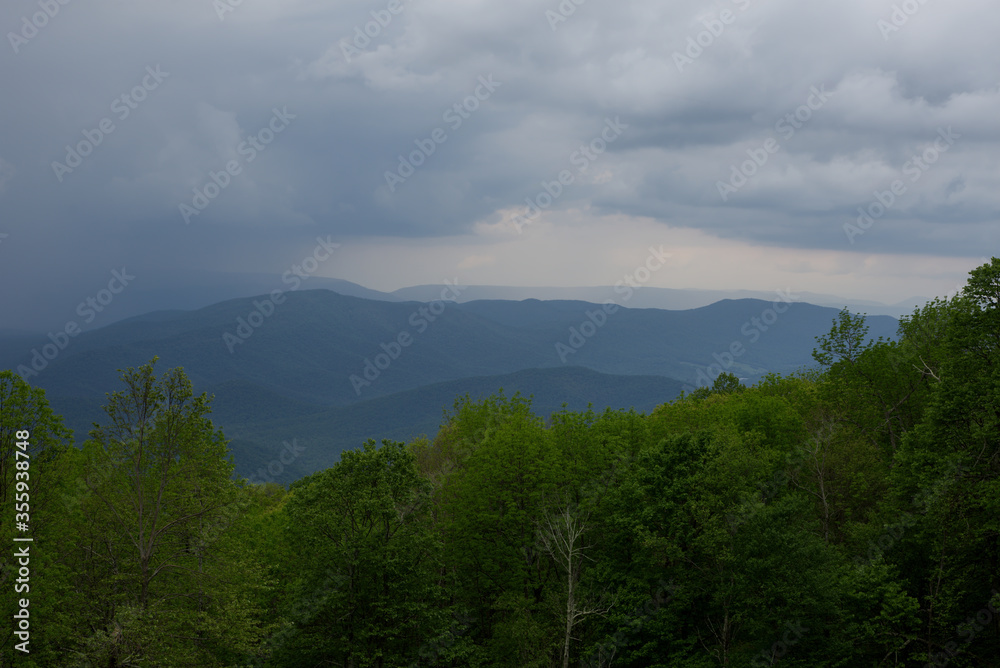 A summer thunderstorm approaches the mountains and the covers the valley below.