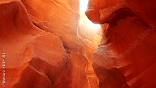 Dust floating around orange sandstone rocks in Antelope Canyon, Arizona, USA. Sun shining through. Steadicam shot, 4K