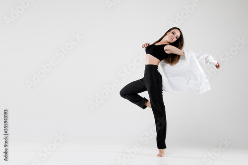 Female dancer in dance jazz poses in a shirt on a white background. Jazz, modern, freedom, feelings, sport, figure, dance.