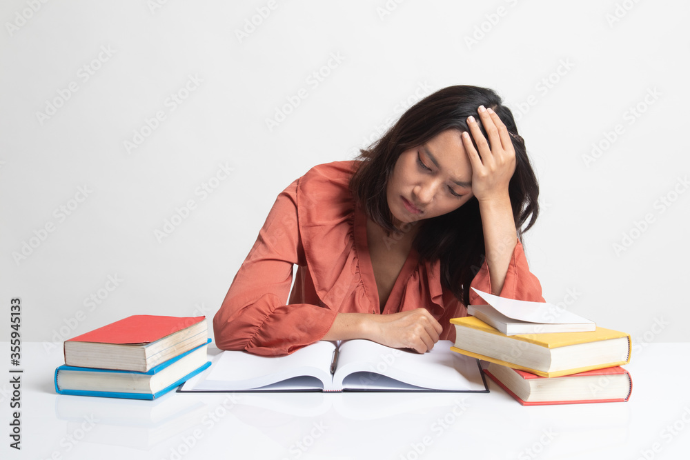 Exhausted Young Asian woman read a book with books on table . Exhausted Young Asian woman read a book with books on table .