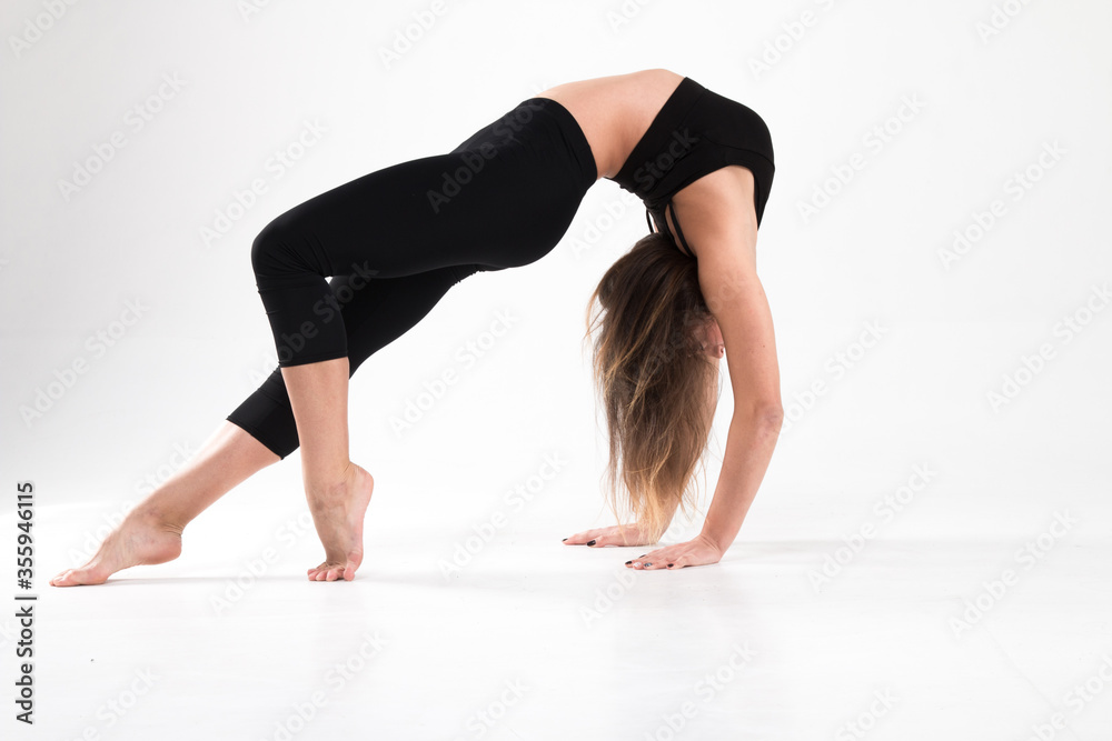 Girl in a gymnastic handstand with a bridge on a white background. Gymnastics, rhythmic gymnastics, practice, workout, strength, flexibility, stretching, performance. Girl in a gymnastic handstand with a bridge on a white background. Gymnastics, rhythmic gymnastics, practice, workout, strength, flexibility, stretching, performance.