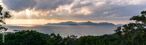 panoramic view of Seychelles, La Digue at sunset. Landscape with sky and colorful clouds. Sun at twilight on the calm sea on the horizon. View of Praslin island