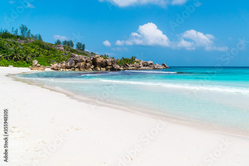 Ocean waves  pristine blue color lagoon and granite rocks on Anse Coco beach  La Digue Island  Seychelles