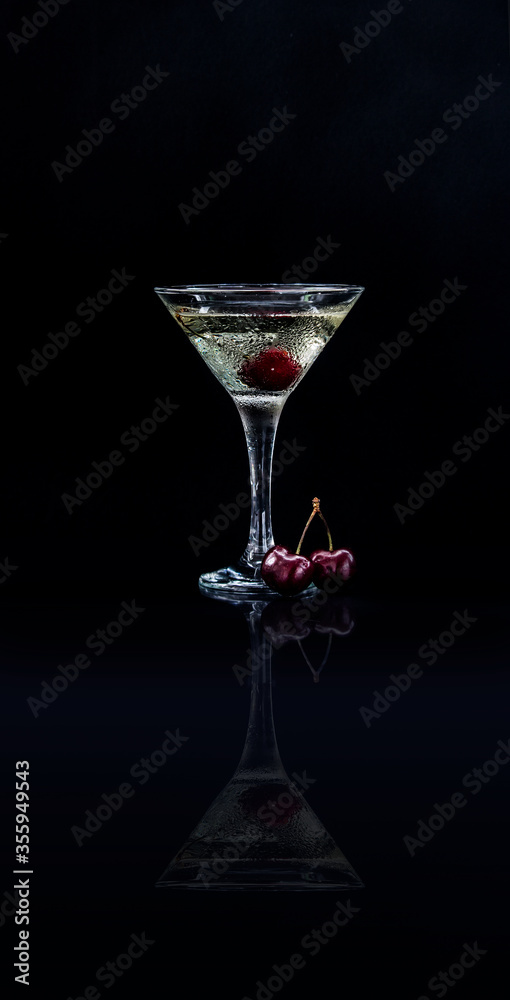 Obraz premium Closeup glass of sweet martini dry cocktail with cherries in black background