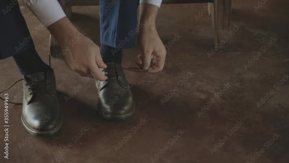 Man tying his shoes while sitting down in his blue suit Man tying his shoes while sitting down in his blue suit