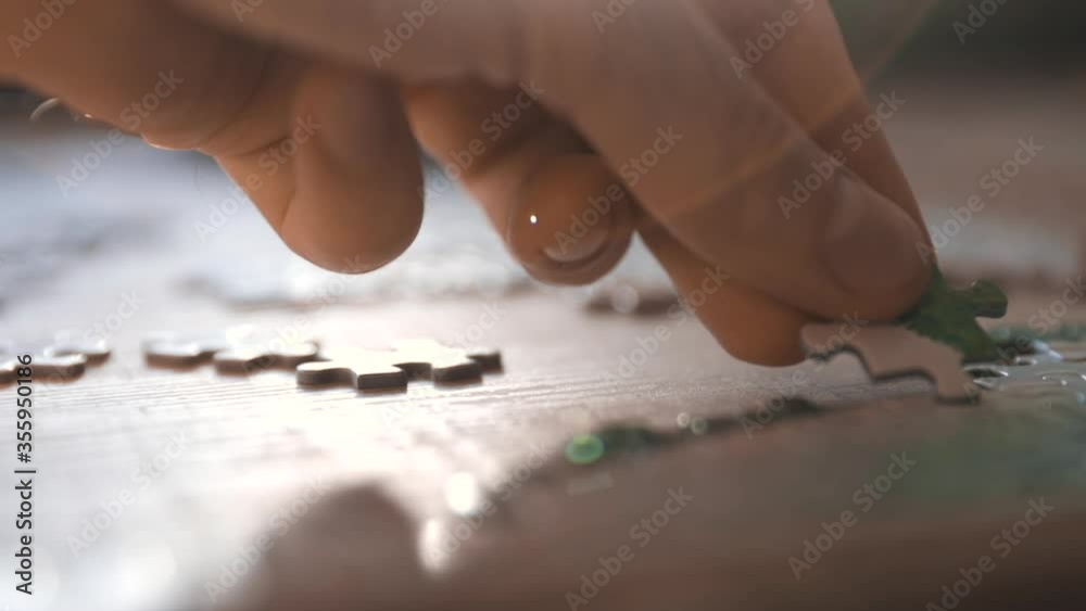 Male hand puzzling, adding pieces to a puzzle- slow motion, tracking shot
