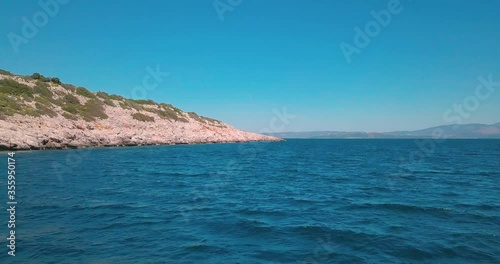 Forward aerial shot next to a rocky shore in the aegean sea, Greece. 4K video quality photo