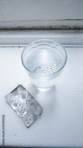 ampoyeta de pastillas vacias en cocina con vaso de agua photo