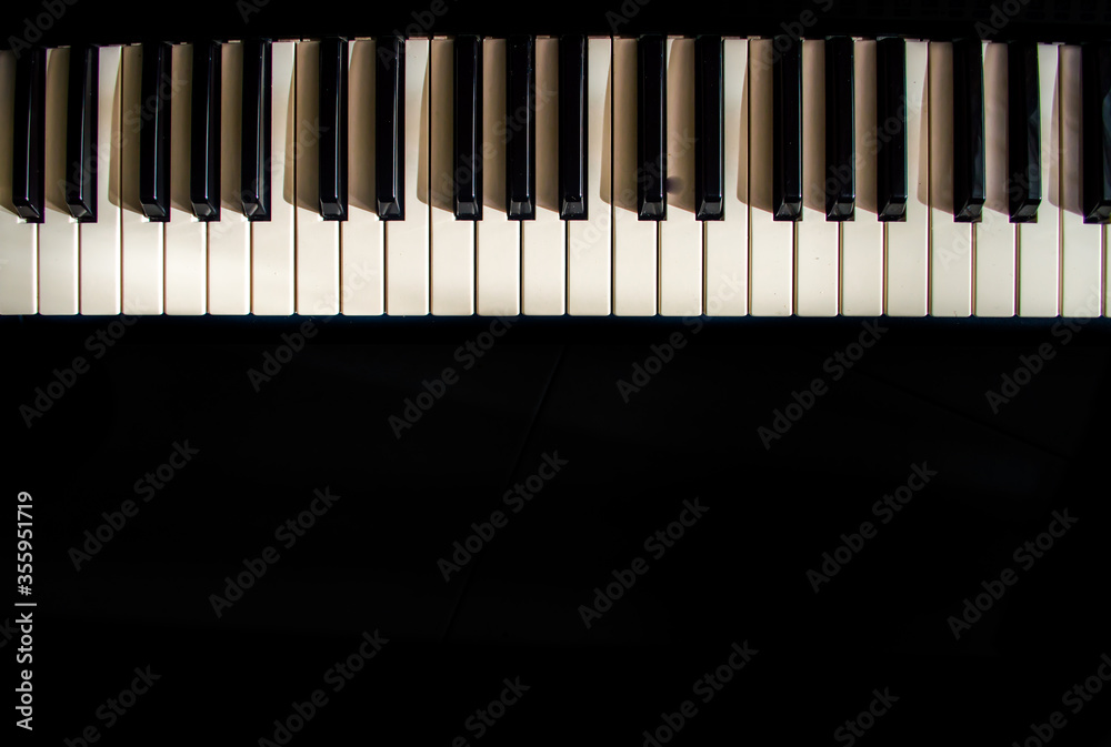 Long contrasted piano in black background 