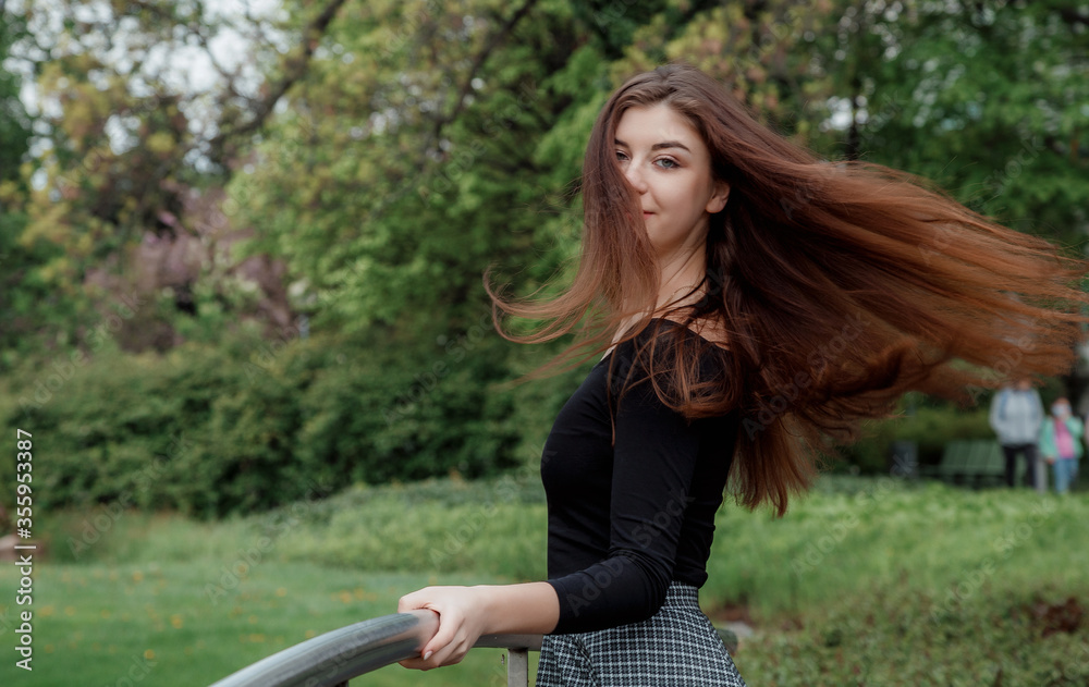 Beautiful girl walks in a green park. Young woman with long black hair ...