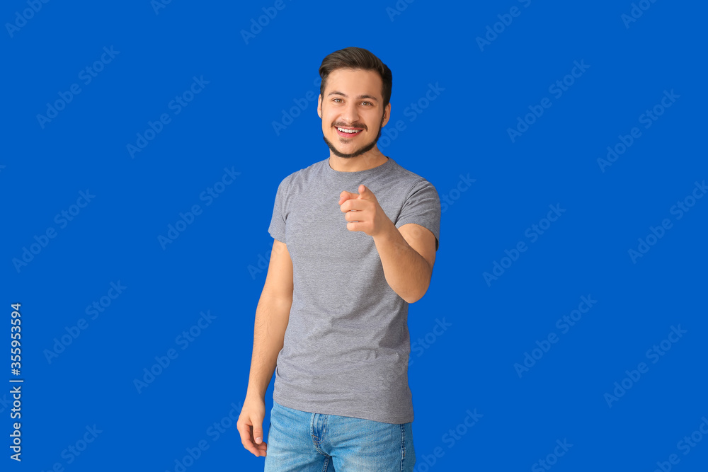 Handsome young man pointing at viewer on color background Handsome young man pointing at viewer on color background