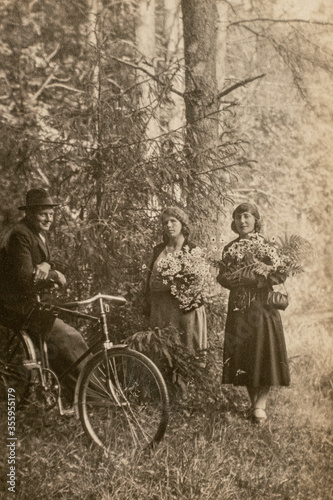 Germany - CIRCA 1930s: Man on bicycle talking with two woman in forest. Vintage archive Art deco era photo