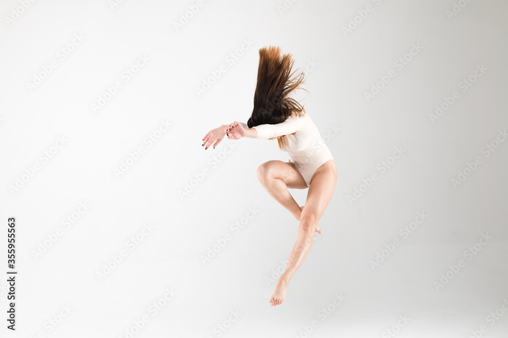 Ballerina in a jump in a beautiful pose with flying hair on a white background. Art, style, background, elegant, expensive, luxury, amazing, modern.