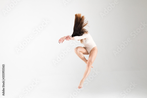 Ballerina in a jump in a beautiful pose with flying hair on a white background. Art, style, background, elegant, expensive, luxury, amazing, modern.