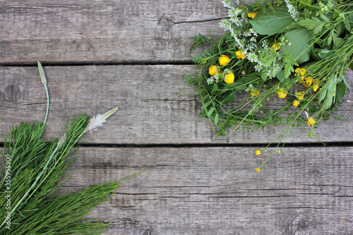 Frame with summer flowers on wooden background. Bunch of green wild plants and yellow buttercups flowers on rustic table