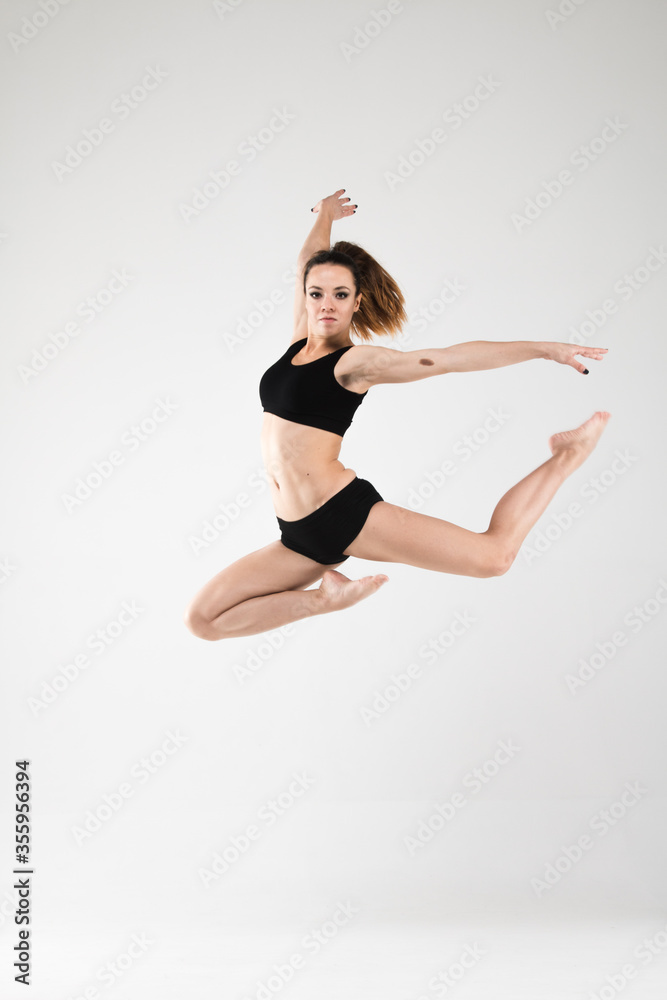 Female dancer in a jump in black clothes on a white background. Jazz, modern, freedom, feelings, sport, figure, dance Female dancer in a jump in black clothes on a white background. Jazz, modern, freedom, feelings, sport, figure, dance