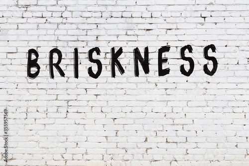 White wall with black paint inscription briskness on it